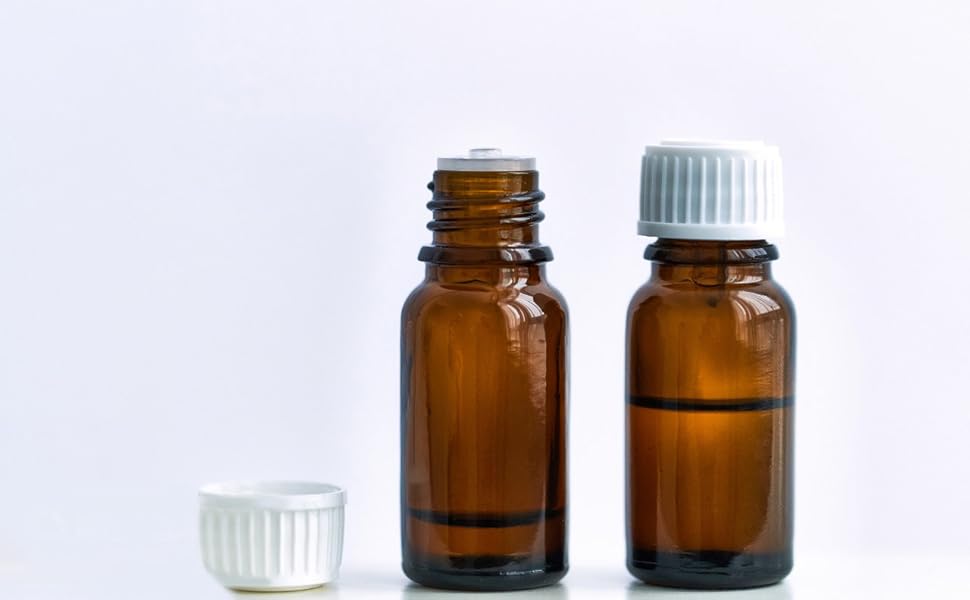 Two amber glass bottles with white caps on a clean white background, one containing dark liquid